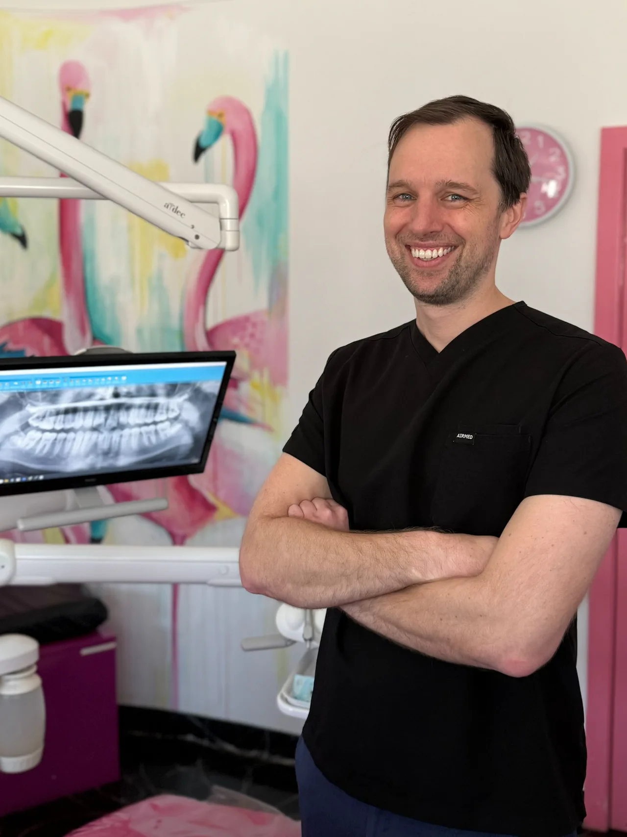Dr David Ward, general dentist, smiling with arms folded in a treatment room at Happy Tooth Kurri Kurri